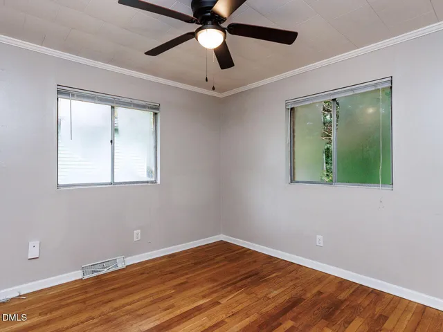 a view of empty room with wooden floor and fan