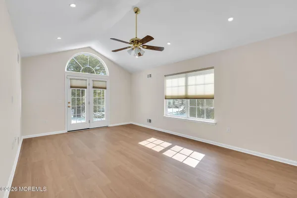 a view of an empty room with a window and wooden floor