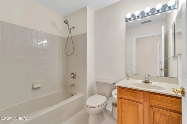 a bathroom with a sink vanity mirror bathtub and toilet