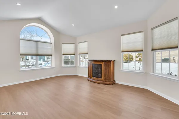 an empty room with windows and fireplace