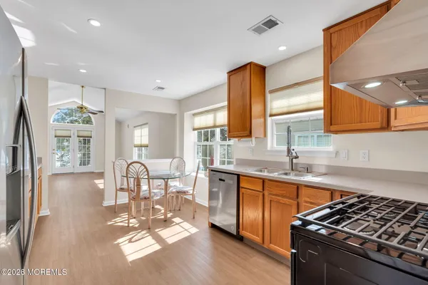 a kitchen with stainless steel appliances granite countertop a stove top oven a sink dishwasher a dining table and chairs with wooden floor
