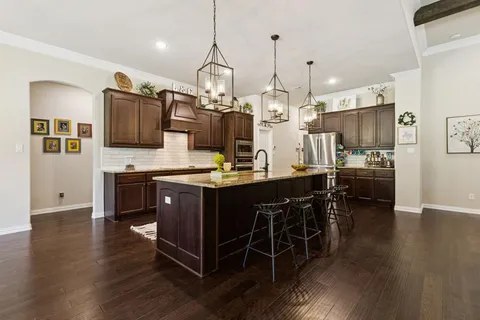 a kitchen with stainless steel appliances kitchen island granite countertop a stove a sink and a wooden floors