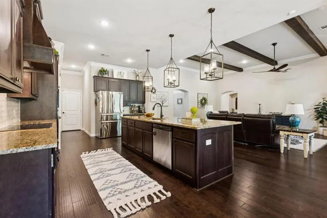 a kitchen with stainless steel appliances granite countertop a sink a stove and a wooden floors