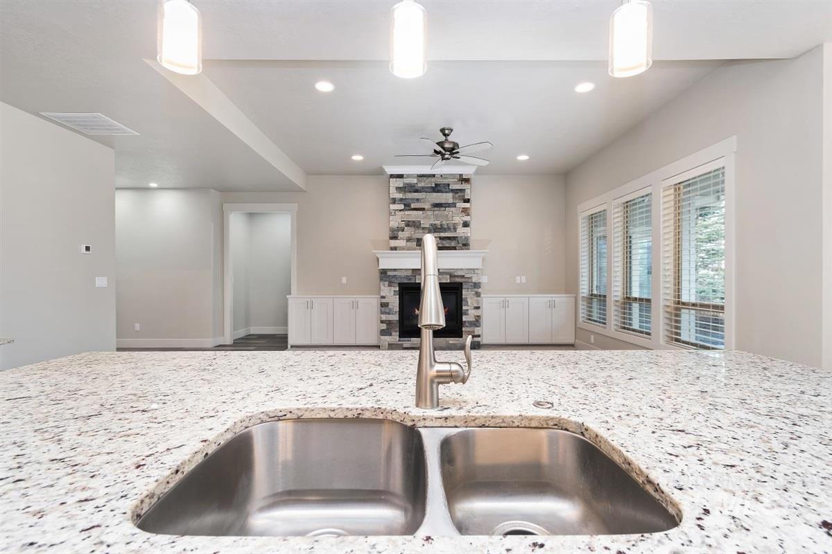 9580 West Ringle Creek Street Star, ID 83669 - Photo 17 of 43 Kitchen with light stone counters, a ceiling fan, a stone fireplace, and hanging light fixtures