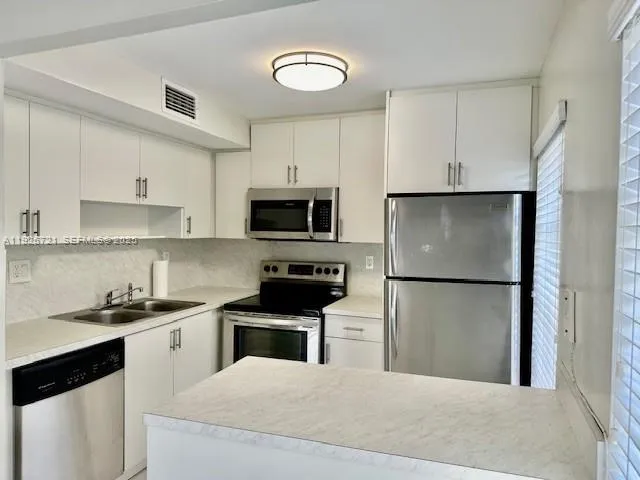 a kitchen with white cabinets and stainless steel appliances