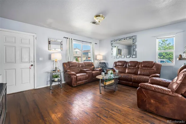 a living room with furniture and a wooden floor
