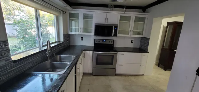 a kitchen with a sink a counter top space stainless steel appliances a window and a sink