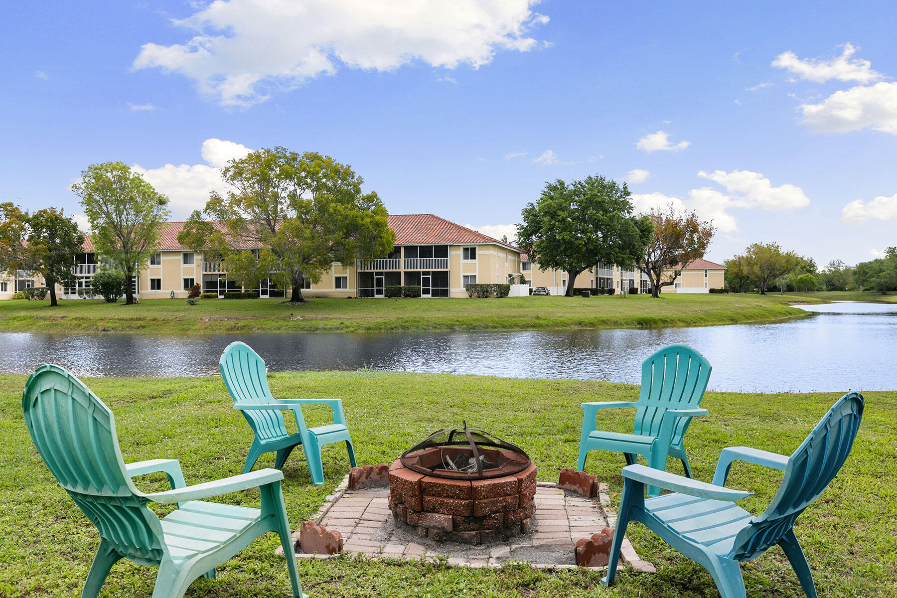 159 Plantation Circle Naples, FL 34104 - Photo 25 of 38 a view of a lake with lawn chairs and a large tree