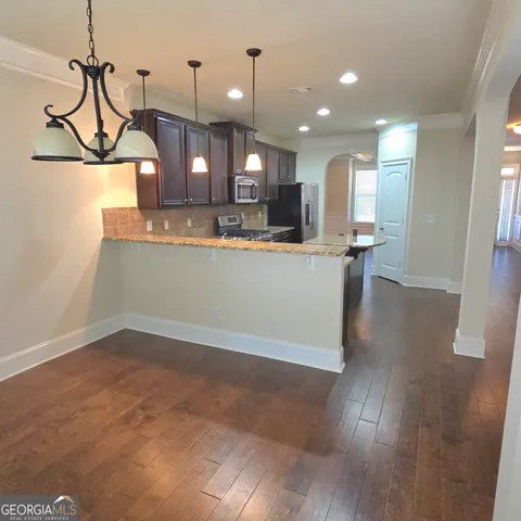 a view of a room with kitchen island stainless steel appliances wooden floor and window