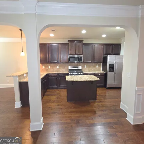 a large kitchen with stainless steel appliances kitchen island granite countertop a refrigerator and a sink