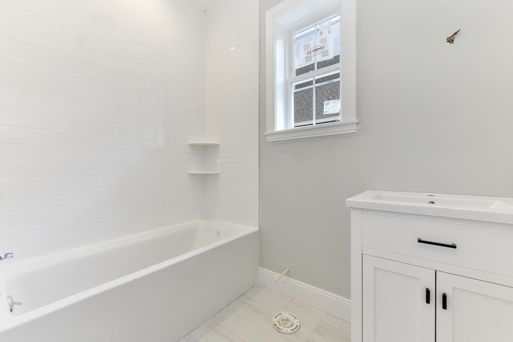 14 Ennis Road, Unit REAR Boston, MA 02119 - Photo 21 of 26 a bath tub sitting next to a white sink and vanity