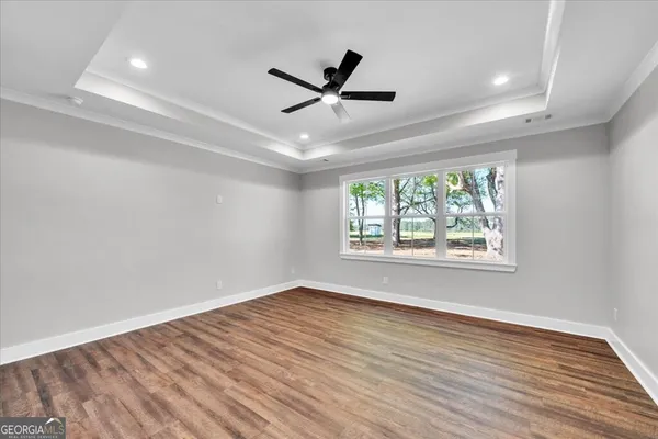 a view of empty room with wooden floor and fan