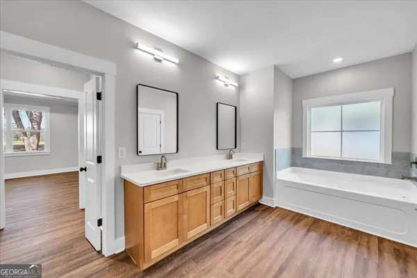 a bathroom with a double vanity sink a mirror and a bathtub