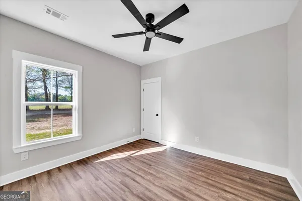 an empty room with wooden floor and windows