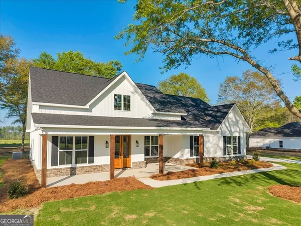 a front view of a house with a garden and trees