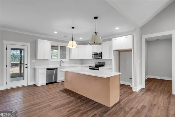 a large kitchen with white cabinets stainless steel appliances a sink and a center island