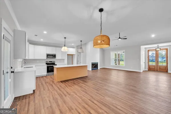 a large kitchen with stainless steel appliances granite countertop a refrigerator a oven a dining table and chairs with wooden floor