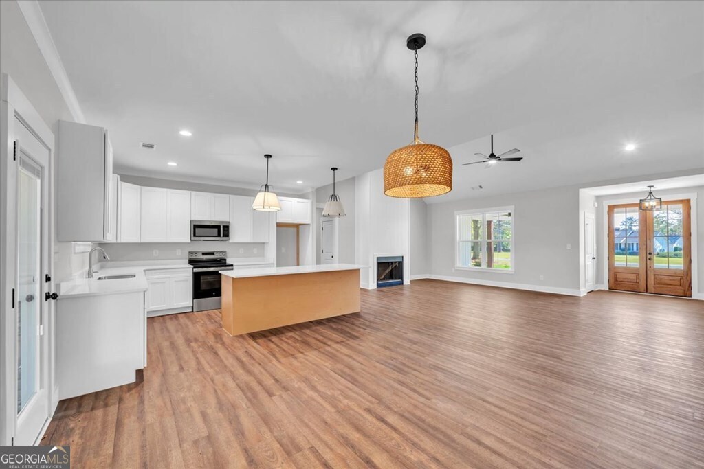 2769 Claxton Dairy Road Dublin, GA 31021 - Photo 7 of 48 a large kitchen with stainless steel appliances granite countertop a refrigerator a oven a dining table and chairs with wooden floor