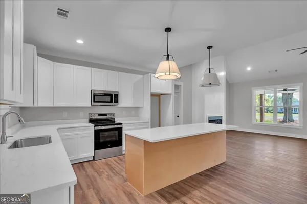 a large kitchen with stainless steel appliances granite countertop a sink a stove and a wooden floors