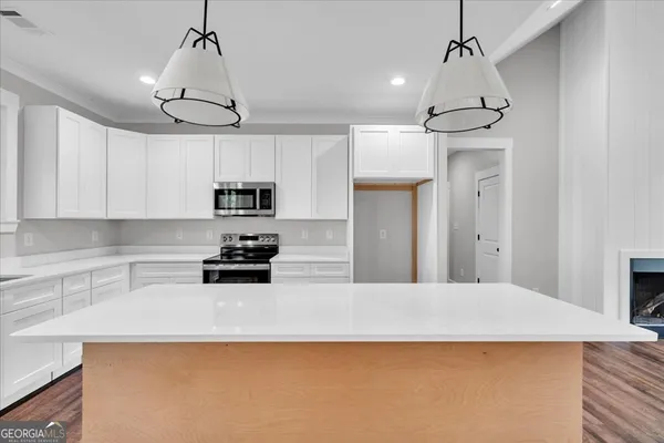 a kitchen with granite countertop a center island a stove a microwave and a refrigerator