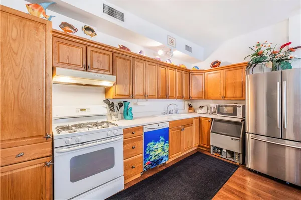 a kitchen with stainless steel appliances white cabinets and wooden floor