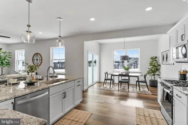 a kitchen with stainless steel appliances granite countertop a stove and white cabinets with wooden floor