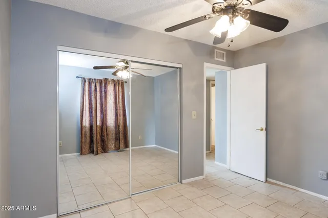 an empty room with closet and a chandelier fan