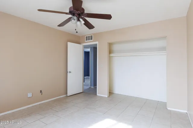 an empty room with windows and chandelier fan