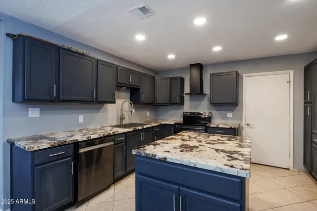 a kitchen with kitchen island granite countertop stainless steel appliances a sink a stove top oven a counter top space and cabinets