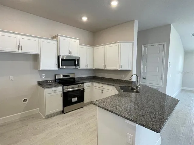 a kitchen with granite countertop a sink and white cabinets
