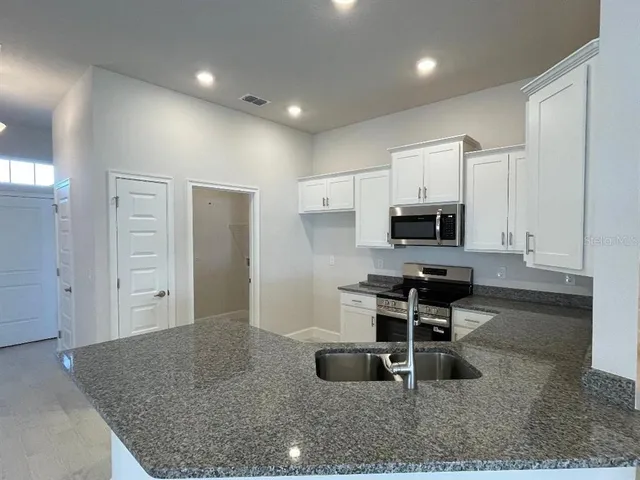 a kitchen with stainless steel appliances kitchen island granite countertop a stove a sink and a refrigerator