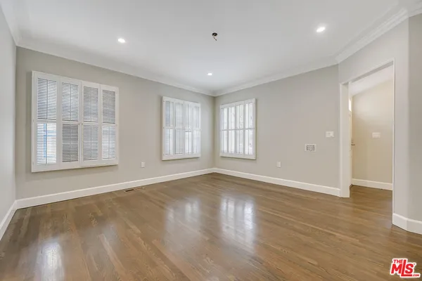 a view of an empty room with wooden floor and windows