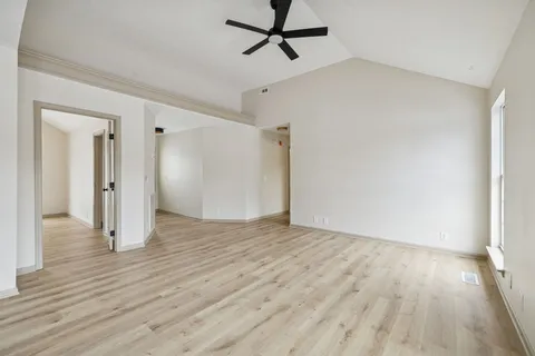a view of empty room with wooden floor and ceiling fan
