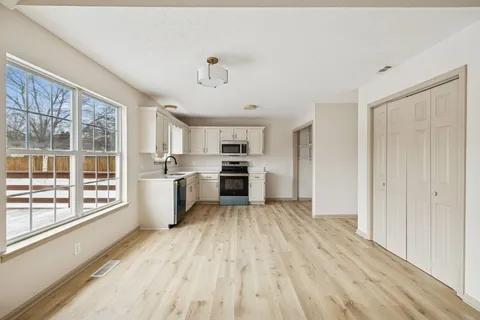 a view of a kitchen with wooden floor electronic appliances and windows