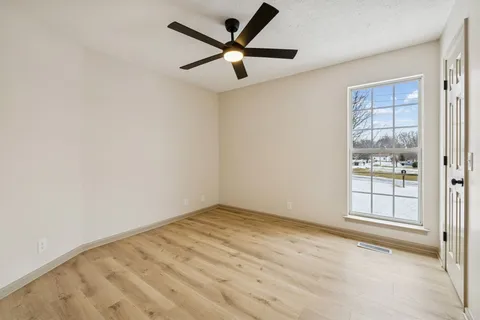 an empty room with windows and fan