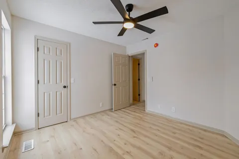 an empty room to hallway with wooden floor