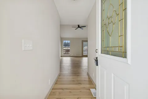 a view of a hallway with wooden floor and a bathroom