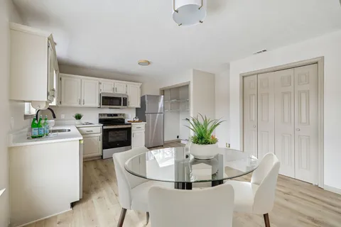 a dining room with furniture a potted plant and kitchen view