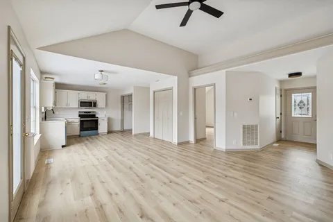 a view of a kitchen with refrigerator and wooden floor
