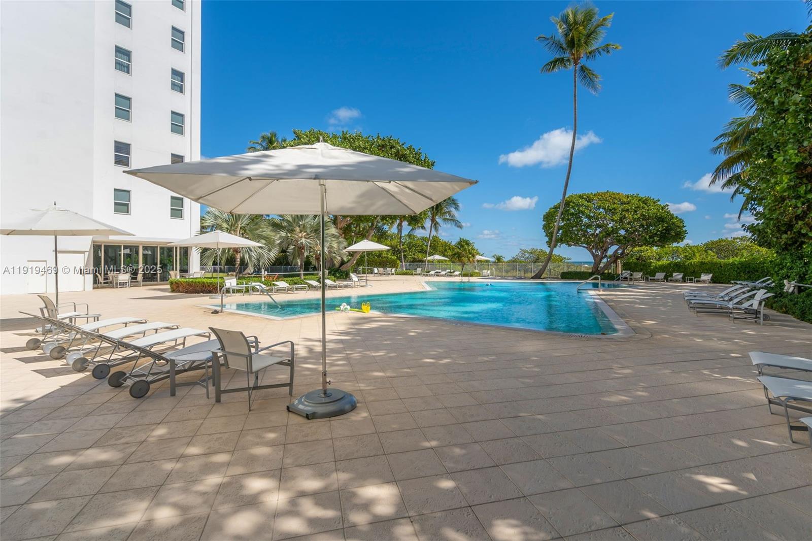 200 Ocean Ln Drive, Unit 407GR09 Key Biscayne, FL 33149 - Photo 36 of 56 a view of a swimming pool with a table and chairs under an umbrella