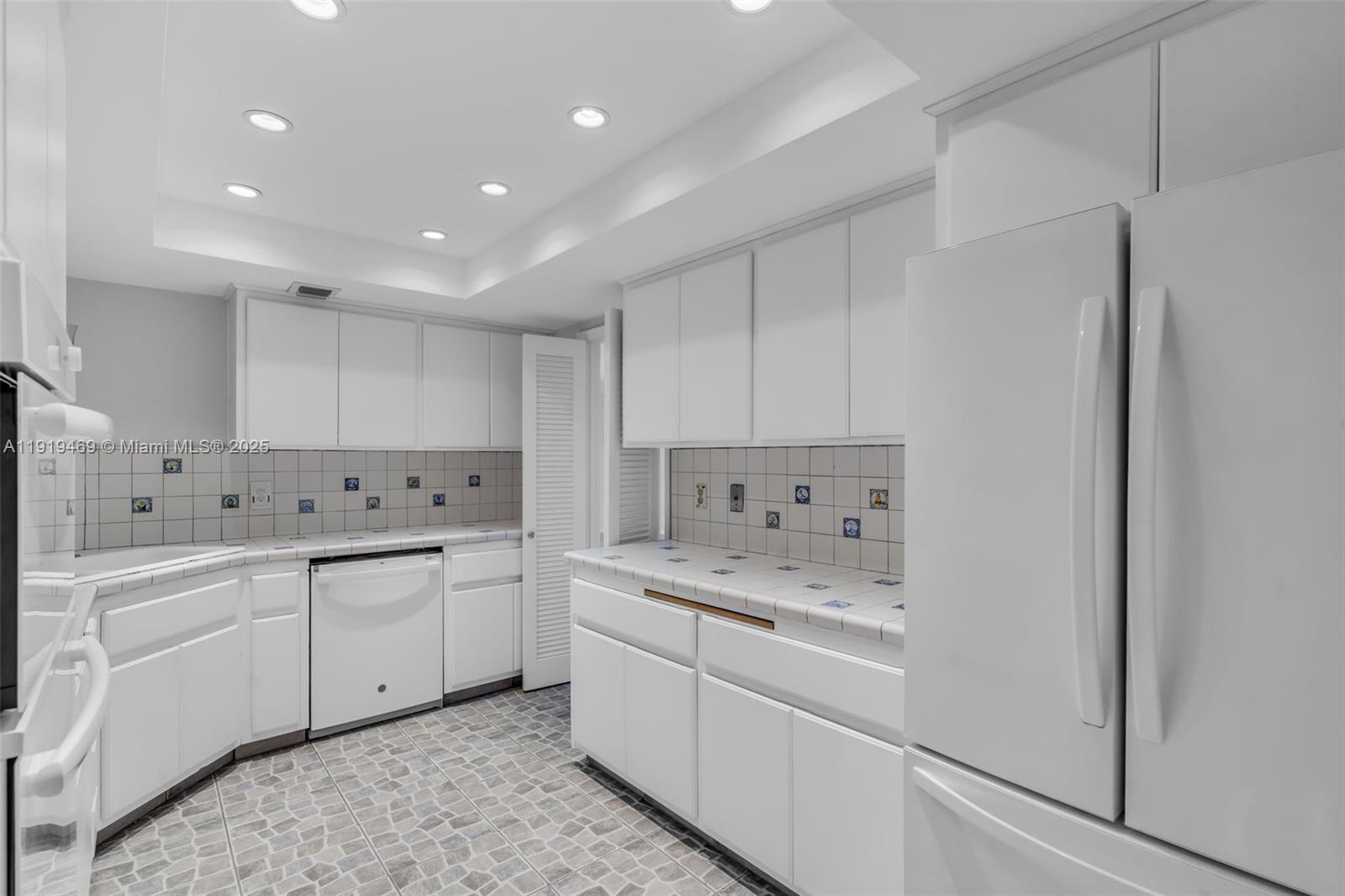 200 Ocean Ln Drive, Unit 407GR09 Key Biscayne, FL 33149 - Photo 10 of 56 a kitchen with white cabinets sink and stove