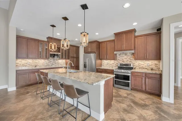 a kitchen with stainless steel appliances kitchen island granite countertop a sink stove and refrigerator