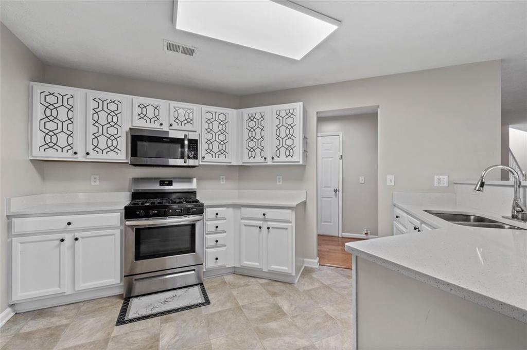 6115 Riveroak Terrace Atlanta, GA 30349 - Photo 14 of 41 a kitchen with stainless steel appliances a stove sink microwave and cabinets