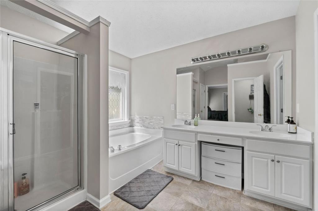 6115 Riveroak Terrace Atlanta, GA 30349 - Photo 33 of 41 a spacious bathroom with a double vanity sink a mirror and a bathtub
