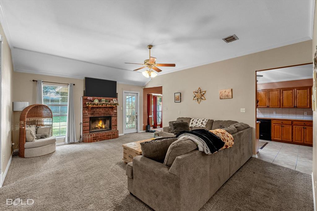 122 Ragan Lane Haughton, LA 71037 - Photo 4 of 34 Vaulted ceiling with a ceiling fan, brick fireplace, large window, and light-colored wall paint