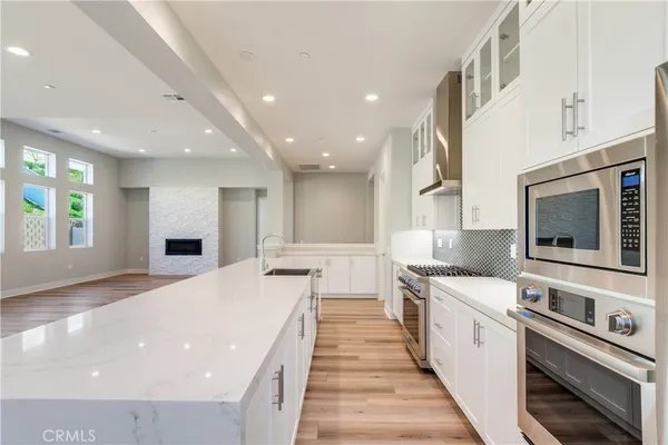 a large kitchen with stainless steel appliances kitchen island a large counter top a stove a chimney a sink and a refrigerator