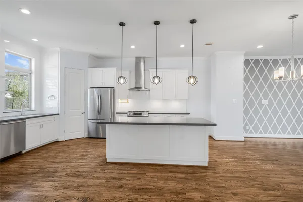 a kitchen with stainless steel appliances granite countertop a sink a stove and a wooden floors