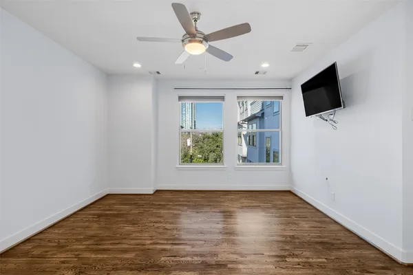 a view of empty room with wooden floor and fan
