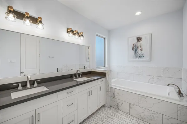 a spacious bathroom with a granite countertop double vanity sink a mirror and bathtub