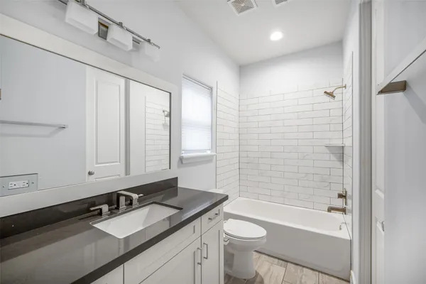 a bathroom with a granite countertop sink toilet mirror and bathtub